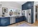 This kitchen features navy cabinets, stainless steel appliances, and a farmhouse sink under a bright window at 1002 Detroit St, Denver, CO 80206