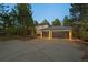 Spacious three-car garage with an expansive driveway, nestled among tall pine trees at 1935 Poncha Ct, Larkspur, CO 80118