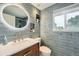 Modern bathroom showcasing stylish tile work, a new vanity, a round mirror, and a well-lit space at 8455 W Belmar Ave, Lakewood, CO 80226