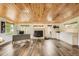 Large bonus room showcasing a wood plank ceiling, tile floors, a brick fireplace, and windows providing ample natural light at 8455 W Belmar Ave, Lakewood, CO 80226