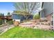 Expansive backyard with lush green grass, mature trees, and a charming stone path at 7411 S Crescent Ct, Littleton, CO 80120