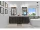 Bright bathroom featuring dual vanity sinks, soaking tub, a chandelier, and natural light at 7411 S Crescent Ct, Littleton, CO 80120