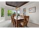 Bright dining room boasts large windows, wooden table with seating, and modern light fixture at 7411 S Crescent Ct, Littleton, CO 80120