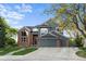 Two-story home features brick and gray siding with a three car garage and manicured lawn at 7411 S Crescent Ct, Littleton, CO 80120