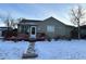 Ranch style home with snow-covered yard, deck and walkway at 11856 E 7Th Ave, Aurora, CO 80010