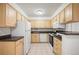 Bright kitchen featuring light wood cabinets, white appliances, and tile flooring at 3335 S Ammons St # 6-102, Lakewood, CO 80227
