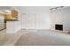 Open-concept living area with a white brick fireplace, neutral carpet, and a partial view of the kitchen at 3335 S Ammons St # 6-102, Lakewood, CO 80227