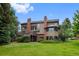 Exterior of home showcasing large windows, brick chimneys, and lush backyard at 9 Red Fox Ln, Littleton, CO 80127