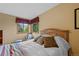 A bedroom features a neutral paint and wooden bed with a view of the outdoor foliage at 9 Red Fox Ln, Littleton, CO 80127