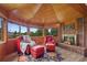The sitting area includes a brick fireplace, bright windows, cozy decor, and comfortable red chairs and ottomans at 9 Red Fox Ln, Littleton, CO 80127