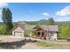 Beautiful home with a covered front porch and an American flag, set against a backdrop of lush trees and mountains at 11033 Barker Ave, Conifer, CO 80433