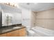 Bathroom featuring a vanity with granite countertop, soaking tub, tile surround, and large mirror at 1700 Bassett St # 703, Denver, CO 80202
