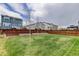 Wide shot of a backyard with well-maintained lawn, garden beddings, and houses with wooden fences at 1246 Blackhaw St, Elizabeth, CO 80107