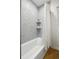 Bathroom with gray tiled walls, a shower-tub combo, and neutral-colored rug at 4419 W 34Th Ave, Denver, CO 80212