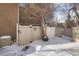 View of a snow covered backyard with a gate and a tree at 9573 E Kansas Cir # 57, Denver, CO 80247