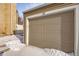 Attached garage with light beige door, snow on ground at 9573 E Kansas Cir # 57, Denver, CO 80247