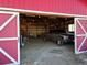 The inside of the barn with a truck, lights, rafters, and a red and white doorway at 10691 County Road 23, Fort Lupton, CO 80621