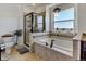 Elegant bathroom with a soaking tub, glass shower, and a large window with a view at 10691 County Road 23, Fort Lupton, CO 80621