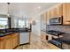 Bright kitchen featuring stainless appliances, black countertops, wood cabinets and an adjoining breakfast nook with outdoor views at 10691 County Road 23, Fort Lupton, CO 80621
