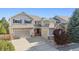 Charming two-story home featuring gray siding, stone accents, a well-manicured lawn, and attached three-car garage at 9636 W 71St Pl, Arvada, CO 80004