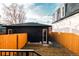 View of a modern, dark accessory dwelling unit (ADU) in the backyard, surrounded by a bright orange fence at 2753 Curtis St, Denver, CO 80205