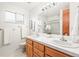 Well-lit bathroom with double sinks, wood cabinets, and a large mirror at 10050 W 8Th Pl, Lakewood, CO 80215