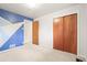 A bedroom with blue accent wall, light carpet and wood doors at 10050 W 8Th Pl, Lakewood, CO 80215