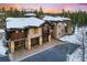 Elegant stone and wood home with multiple garage spaces and a balcony, surrounded by a snowy landscape at 327 Peerless Dr, Breckenridge, CO 80424
