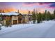 Scenic view of a stone and wood home with a three car garage in a snow-covered, tree-lined setting at 327 Peerless Dr, Breckenridge, CO 80424