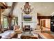 Elegant living room featuring a stone fireplace, chandelier, beamed ceilings, and large windows offering natural light at 327 Peerless Dr, Breckenridge, CO 80424