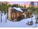 Picturesque home with stone chimney, outdoor seating area and a cozy firepit in a snowy backyard setting at 327 Peerless Dr, Breckenridge, CO 80424