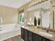 Bathroom featuring a soaking tub, double vanity with granite countertop, and wood look flooring at 8380 Blackgum St, Parker, CO 80134