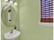 A cozy powder room featuring a pedestal sink, mirror, and green walls at 8380 Blackgum St, Parker, CO 80134