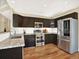 A modern kitchen features dark cabinets, stainless steel appliances, granite countertops, and wood floors at 8380 Blackgum St, Parker, CO 80134