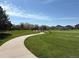 A paved walking path winds through lush green grass and mature trees, ideal for a morning stroll at 8380 Blackgum St, Parker, CO 80134