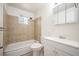 A bright bathroom featuring a vanity, toilet, and a shower-tub combo with beige tiling at 7987 Durango St, Denver, CO 80221