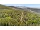 Expansive aerial view featuring a winding dirt road cutting through a dense forest with rolling hills in the background at 154 Apache Rd, Evergreen, CO 80439