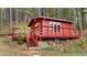 Charming red cabin featuring a cozy front porch and nestled within a serene, tree-filled landscape at 154 Apache Rd, Evergreen, CO 80439