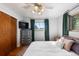 Sunlit bedroom features a vintage ceiling fan, large window, hardwood flooring, and grey dresser at 7216 S Lincoln Way, Centennial, CO 80122