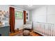 Charming Bedroom with crib, accent chair, vintage rug, and window with rust-colored curtains at 7216 S Lincoln Way, Centennial, CO 80122