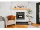 Living room features a modern fireplace with wooden mantle, an accent chair, and hardwood floors at 7216 S Lincoln Way, Centennial, CO 80122