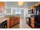 Well-equipped kitchen with wooden cabinets, and black appliances offering seamless flow to an adjacent dining area at 7440 S Blackhawk St # 207, Englewood, CO 80112