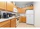 Efficient galley kitchen, features white appliances and light wood cabinets at 7877 E Mississippi Ave # 604, Denver, CO 80247