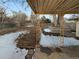 View of the backyard with a covered patio and a large tree, partly covered with snow at 1920 Alton St, Aurora, CO 80010