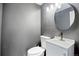 Powder room featuring vanity with white basin sink and modern faucet, and a stylish round mirror at 4860 E 120Th Pl, Thornton, CO 80241