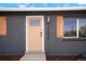 Close-up of the front door with modern light fixture and house number against the gray brick at 13202 Olmsted Pl, Denver, CO 80239