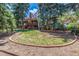 Large backyard with a wood balcony and patio area, surrounded by mature trees providing shade and privacy at 5365 W Princeton Dr, Denver, CO 80235