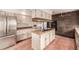Traditional kitchen featuring a center island cooktop, brick accents, and stainless steel refrigerator at 5365 W Princeton Dr, Denver, CO 80235