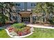 Condo building entrance with manicured flower bed and surrounding foliage at 705 S Alton Way # 6B, Denver, CO 80247