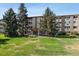 Exterior building view with manicured lawn, trees, and building address at 705 S Alton Way # 6B, Denver, CO 80247